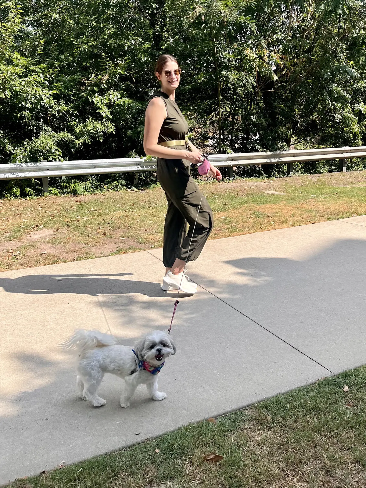 Kimberly walking a small white dog along a sidewalk